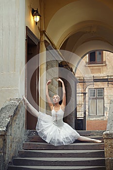 Beautiful ballerina dancing near an old building