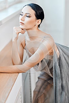 Beautiful ballerina in stage grey loose long transparent dress portrait