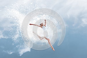 Beautiful ballet dancer jumping inside cloud of powder