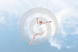 Beautiful ballet dancer jumping inside cloud of powder