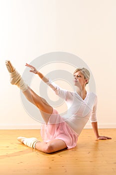 Beautiful ballet dancer lifting arm towards leg