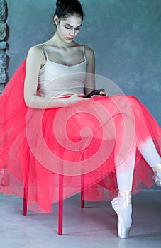 Beautiful ballet dancer sitting in relax with phone