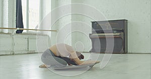 Beautiful ballet dancer stretching out muscles