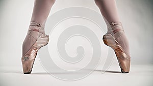 Beautiful ballet feet Pointe shoes stand in a pose from the ballet. Ballerina On a white background. Classical dance. Slow motion