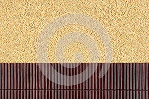 Beautiful bamboo mat on millet grains as agricultural background.