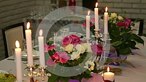 Beautiful banquet table setting with burning candles and fresh flowers. Romantic candlelit dinner.