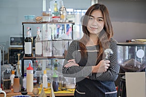 Beautiful barista holding portafilter and smiling to camera while standing in a cafe.