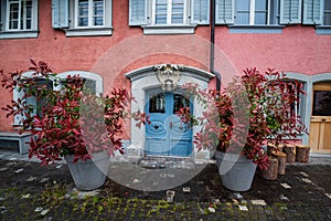 Beautiful baroque door in old house and two flowerpots with red leaf plants, Zug, Switzerland