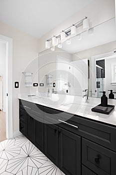 A beautiful bathroom with a black cabinet and pattern tile floor.