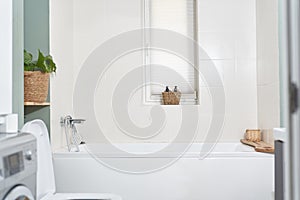 Beautiful bathroom in a new luxury house. The room has an elegant bathroom, a washing machine and a window.