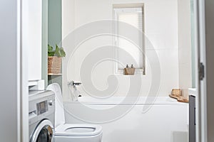 Beautiful bathroom in a new luxury house. The room has an elegant bathroom, a washing machine and a window.