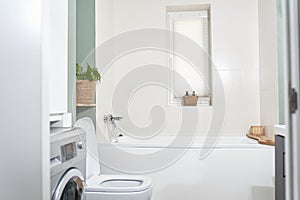 Beautiful bathroom in a new luxury house. The room has an elegant bathroom, a washing machine and a window.