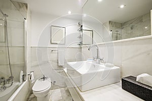 Beautiful bathroom with white marble tiles with a mirror integrated into the wall, an educational cabin with a glass partition and