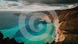 Beautiful bay with brown rocky limestone coastline and moving dramatic clouds on horizon, Assos, Kefalonia island