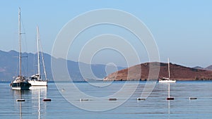 Beautiful bay with calm blue sea, sailboats, islands and mountains