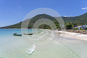 Beautiful bay with coconut palm trees and boats. Tropical sand beach and sea water on island Koh Phangan, Thailand