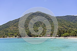 Beautiful bay with coconut palm trees and boats. Tropical sand beach and sea water on island Koh Phangan, Thailand