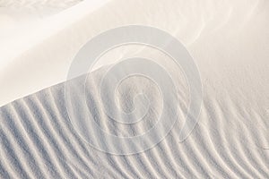 Beautiful beach background. Sand, wave, reflect, shadow, light, beige. Patterns in sand of dune like ruffle in water