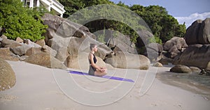 Beautiful beach bay with woman in deep meditation, she sits on sport mat
