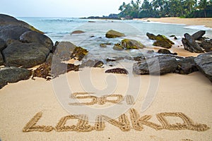 Beautiful beach with palm trees and boulders on the tropical island of Sri Lanka.