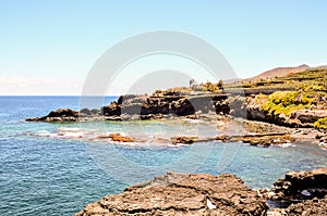 A beautiful beach with a rocky shoreline and a clear blue ocean