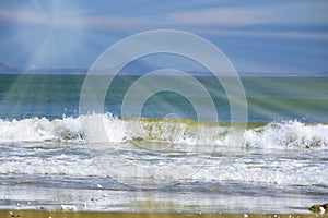 Beautiful beach, on the sand roll frothy waves