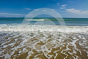 Beautiful beach, on the sand roll frothy waves