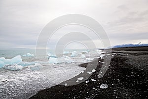 Beautiful beach in South Iceland with black lava sand and icebergs from glaciers