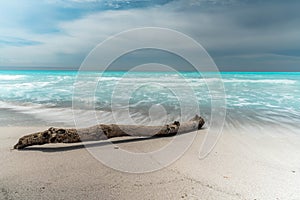 Beautiful beach with turquoise water and white sand. Wooden stick on beach