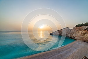 Beautiful beach and water bay in the greek spectacular coast line. Sunset gorgeous sky over blue water unique rocky cliffs. Greece