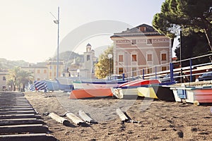 Beautiful beach with yellow sand and colorful boats in old Italian town Sestri Levante Liguria on sunset