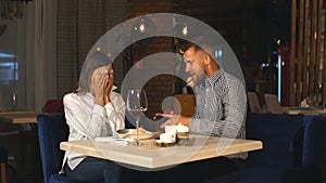 A beautiful bearded man gives a gift to his girlfriend in a restaurant