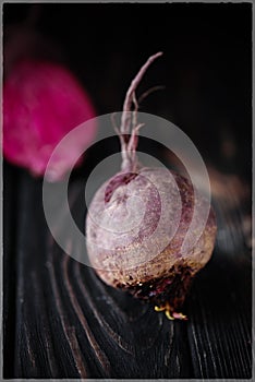 Beautiful beetle on a black background. Red beet in a dark key on a black table