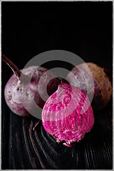 Beautiful beetle on a black background. Red beet in a dark key on a black table