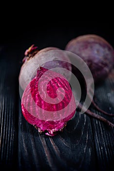 Beautiful beetle on a black background. Red beet in a dark key on a black table