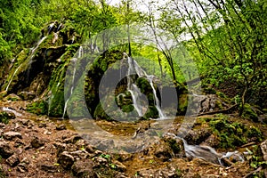 Beautiful Beusnita waterfall in the forest with green moss