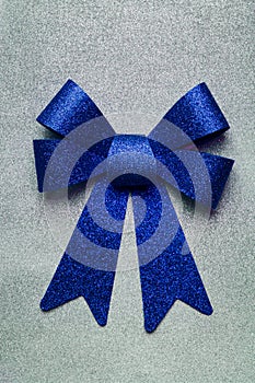 A beautiful big blue bow on a silver glittering background