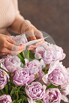 Beautiful big bouquet of double violet tulip flowers with blank greeting card on a dark rustik background. Place for text
