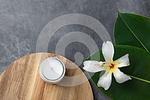 Beautiful big green ficus leaves tropical flower candle wood board gray cement background. Organic Cosmetics Wellness spa