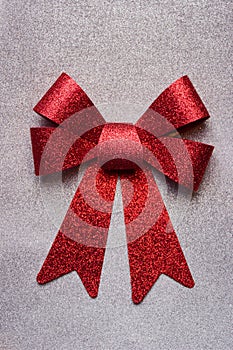 A beautiful big red bow on a silver glittering background.