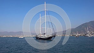 Beautiful big yacht anchored in the blue calm sea against the background of beautiful small mountains and ships on a