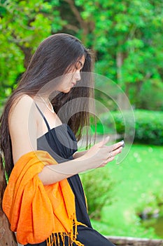 Beautiful biracial teen girl using cellphone with greenery in ba