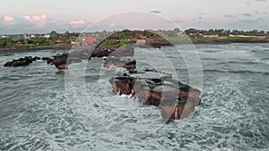 A beautiful bird's-eye view of flying around the black rocks on ocean at the golden hour. Panoramic shots of the