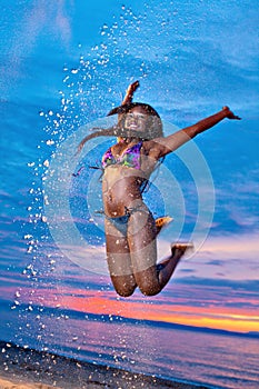 Beautiful black African American woman jumping on the beach