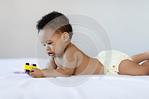 Beautiful Black Baby Playing With Toy While Relaxing On Bed At Home