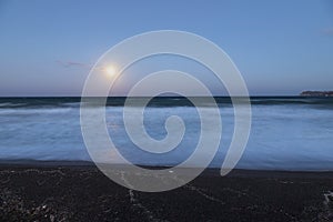 Beautiful black beach with coast and sea in Vlichada with blue sky background with white clouds and sea