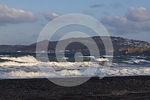 Beautiful black beach with coast and sea in Vlichada with blue sky background with white clouds and sea