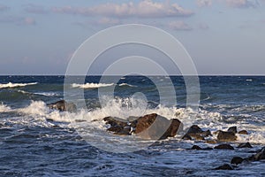 Beautiful black beach with coast and sea in Vlichada with blue sky background with white clouds and sea