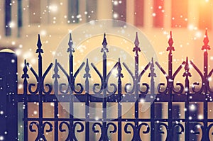 Beautiful black cast-iron fence with artistic forging. Beautiful winter background with falling snow