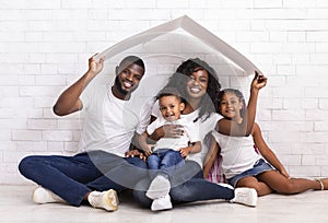 Beautiful Black Family Holding Cardboard Roof Dreaming Of New Home
